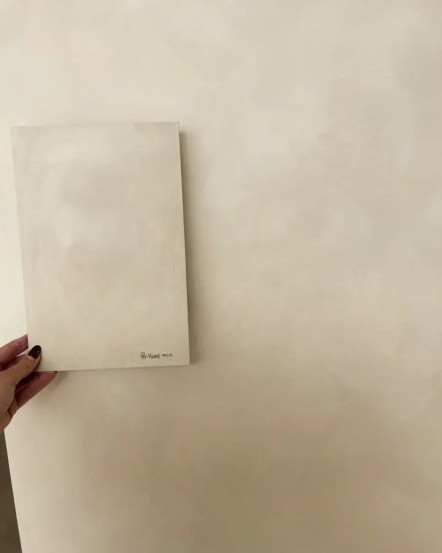Light-coloured surface sample held against a wall